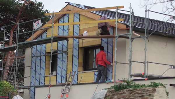 Des couvreurs réalisant des travaux de bardage de façade extérieur d'une maison