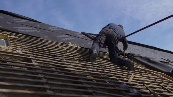Un couvreur réalisant la rénovation d'une toiture