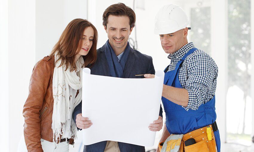 Un couple de propriétaires souriants, avec l'expert travaux